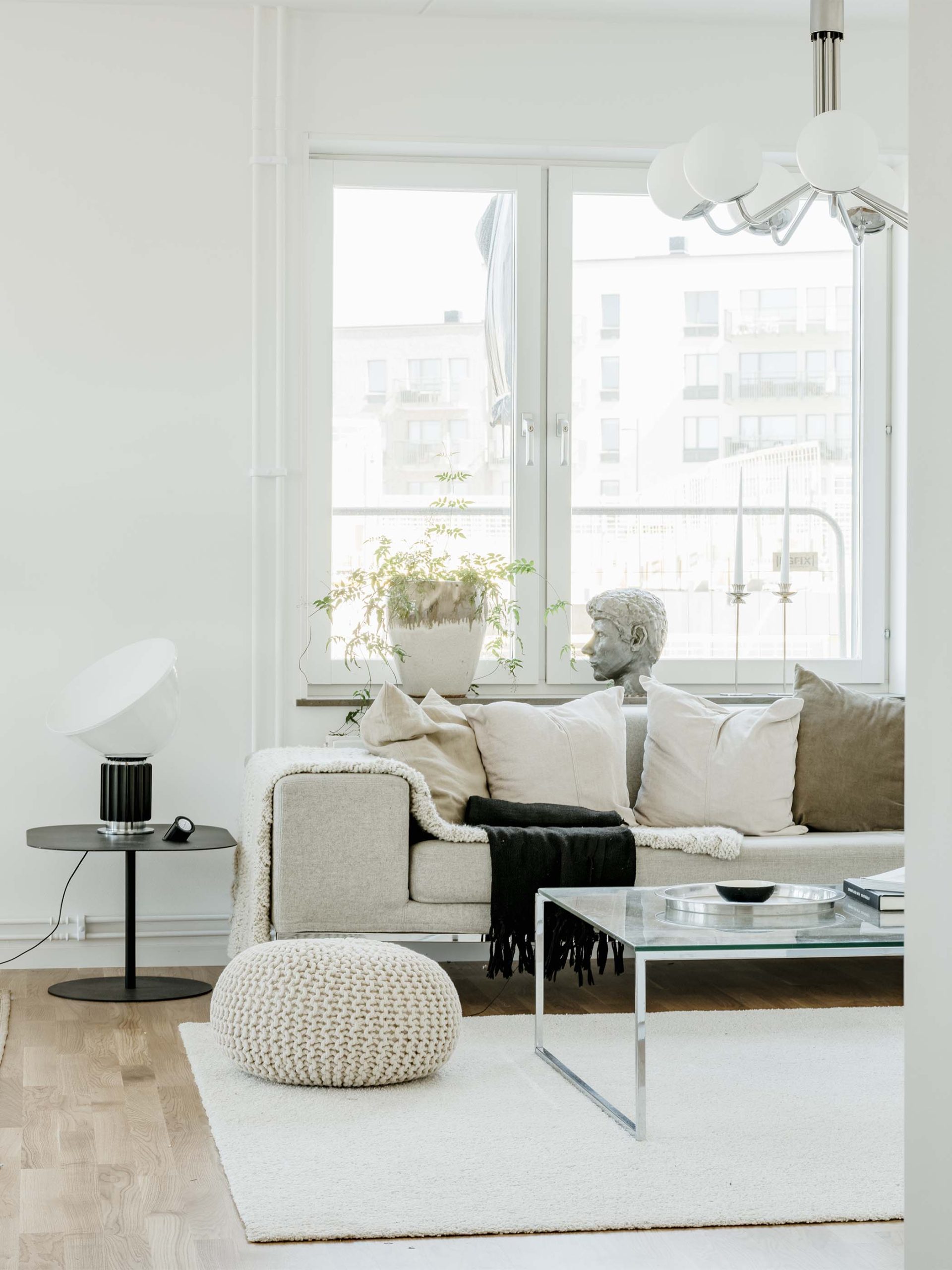 Ett inrett vardagsrum med en beige soffa och vit matta.